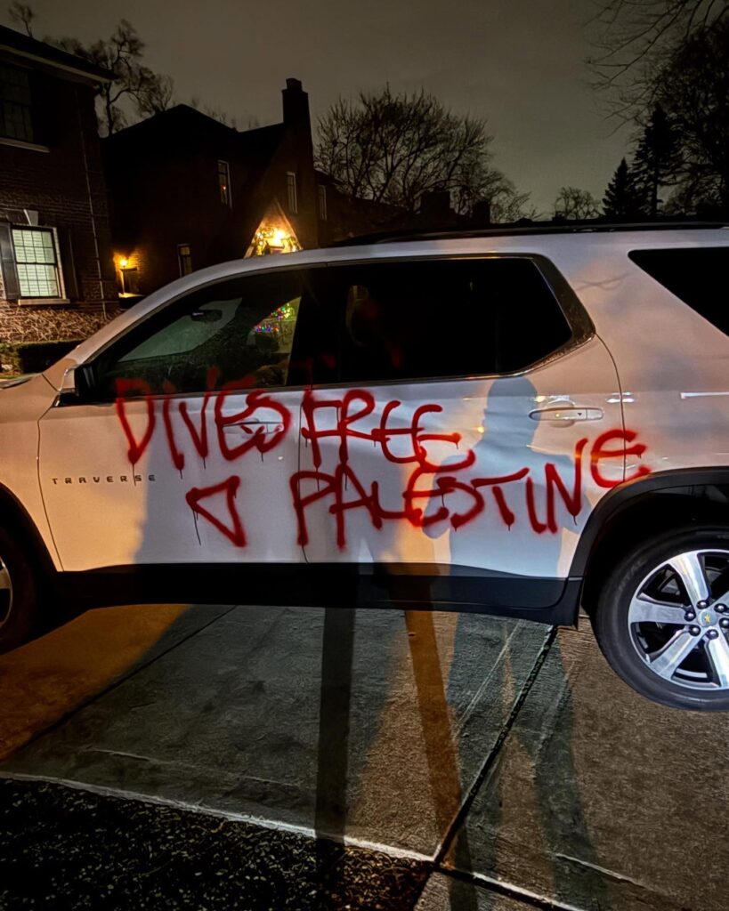 White vehicle with red spray-painted writing 